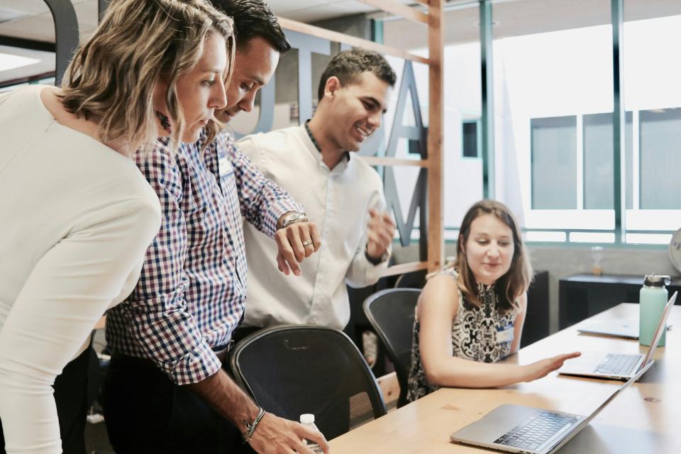 Group of colleagues collaborating around a laptop