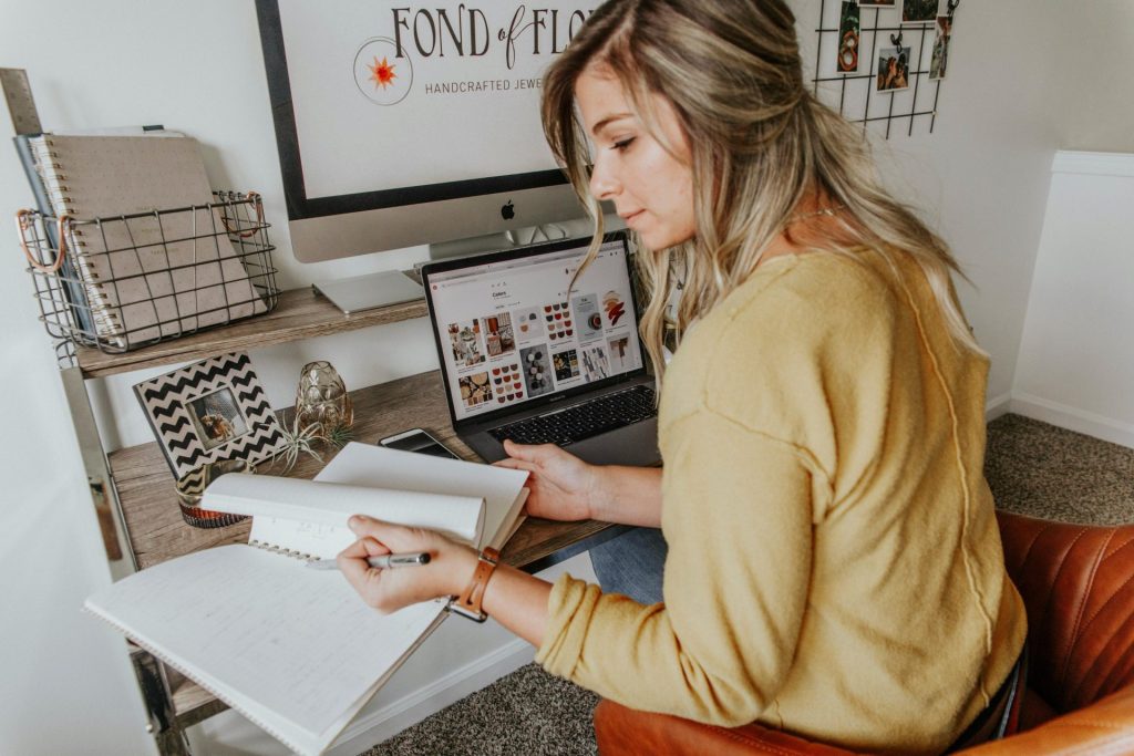 Woman working at desk with laptop, notebook