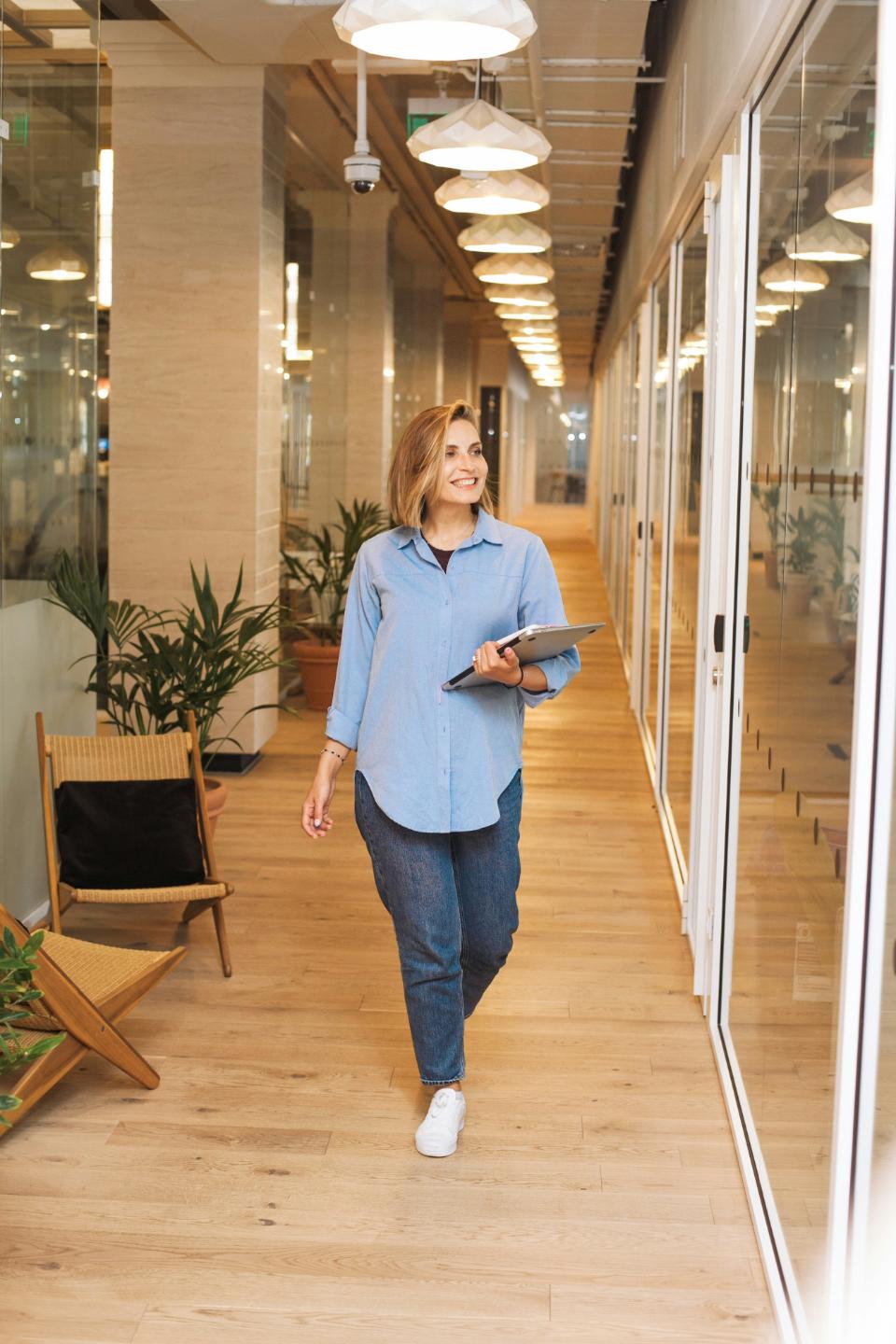 Woman walking in office hallway holding tablet